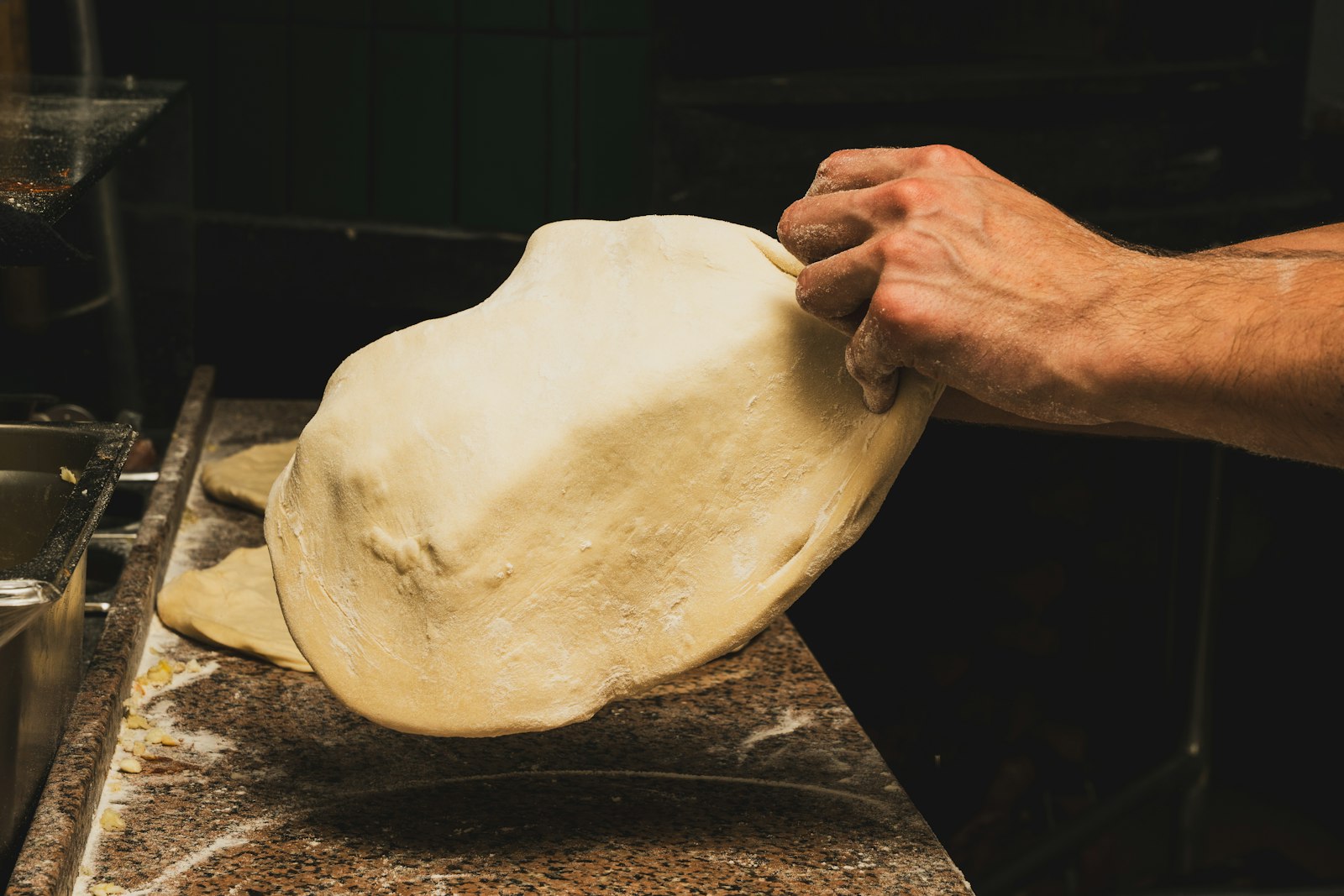 Baker stretching pizza dough by hand